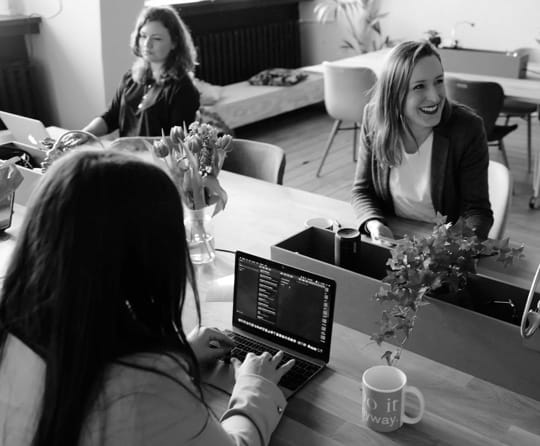 image of three women working, one is smiling.
      